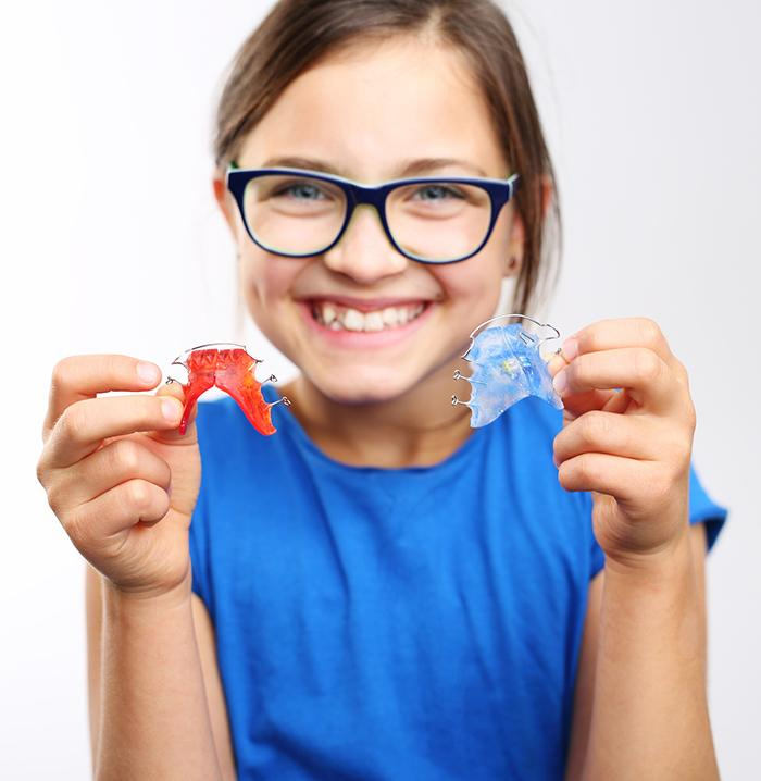 Young girl holding dentofacial orthopedic appliances