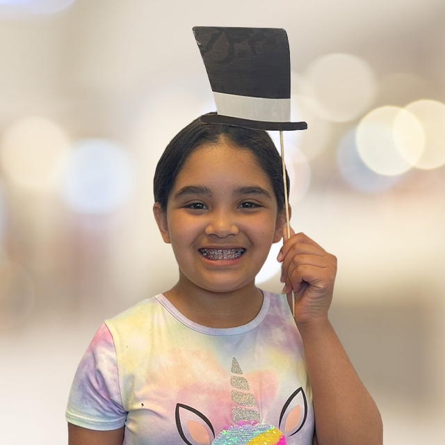 Little girl with braces taking photo with paper hat