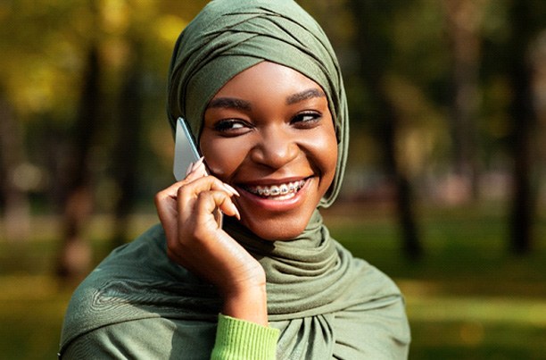 Woman with braces smiling while talking on phone