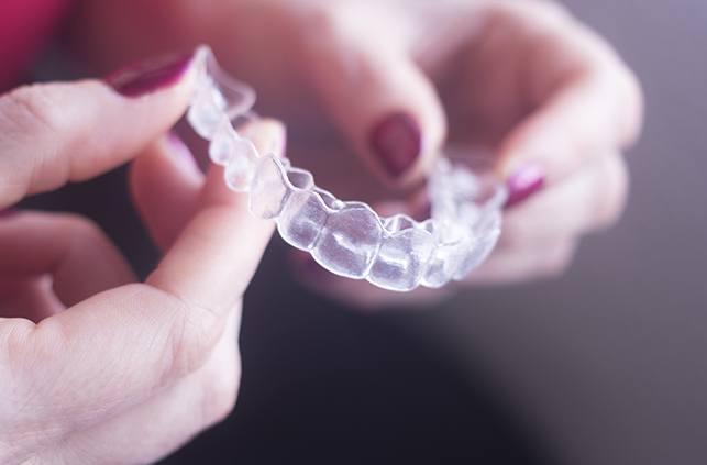 Person holding Invisalign clear braces tray