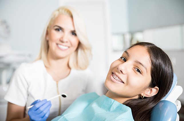 Young woman with traditional braces smiling during orthodontic visit