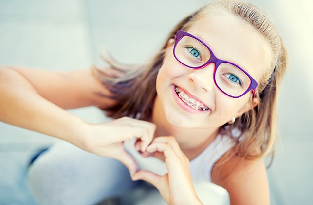 Young girl with traditional braces smiling outdoors