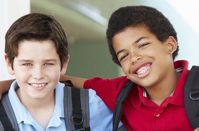 Two young boys smiling one has traditional braces