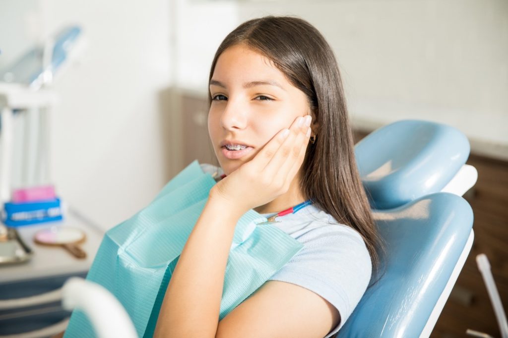 Closeup of teen girl struggling with mouth sore at appointment