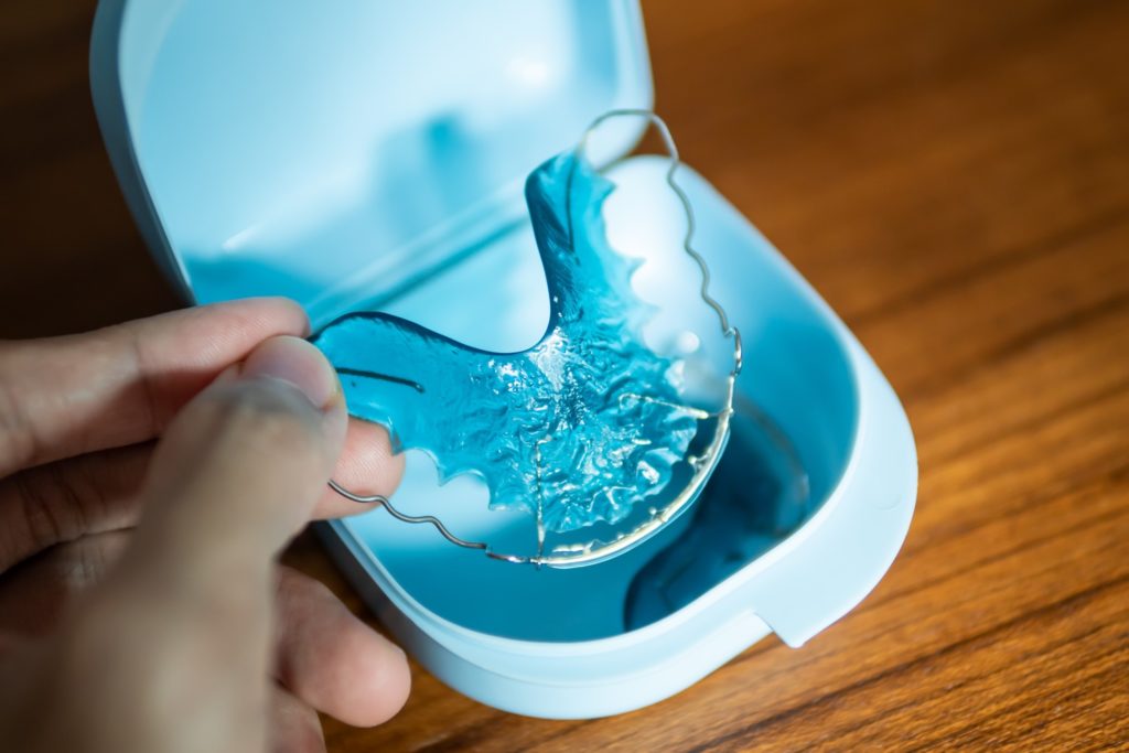 Patient placing blue dental retainer in storage case