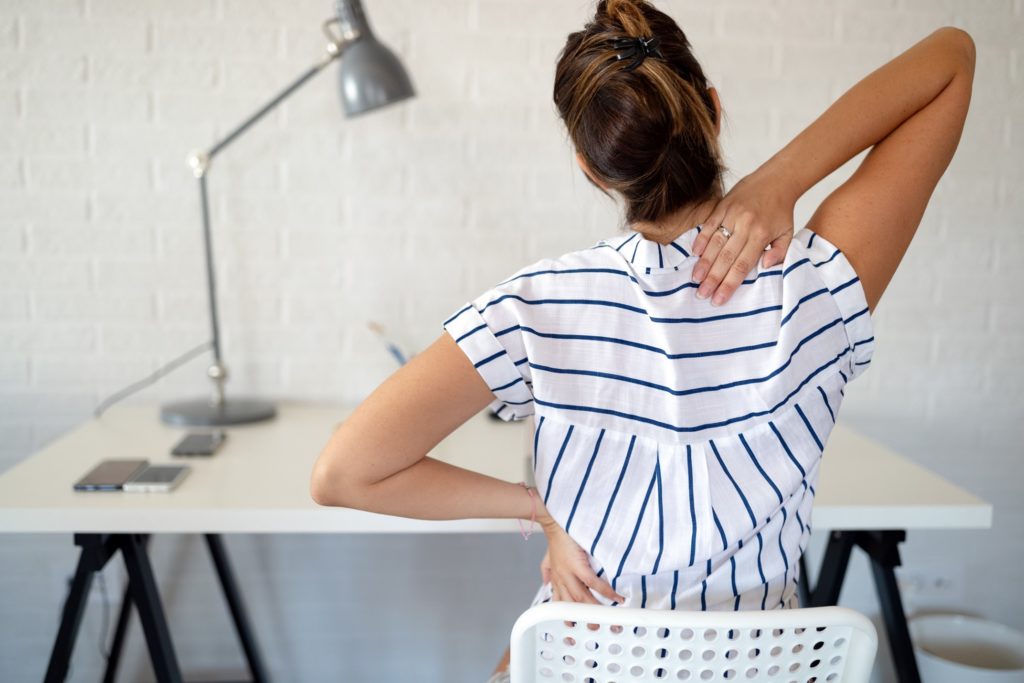 Woman adjusting her posture at her desk