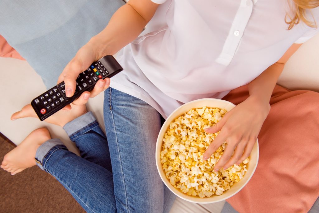 Closeup of woman eating popcorn while relaxing on couch