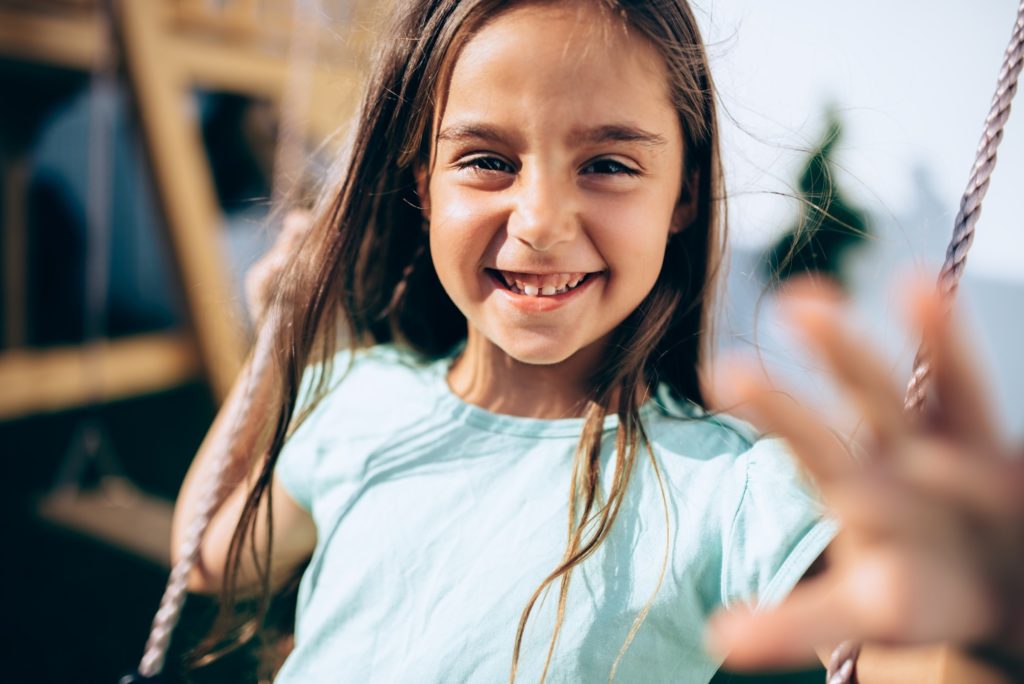 Closeup of young girl smiling while swinging