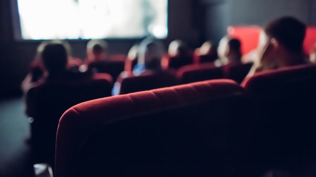 People in movie theatre sitting in red seats