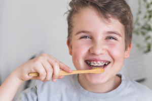 a patient with braces brushing their teeth