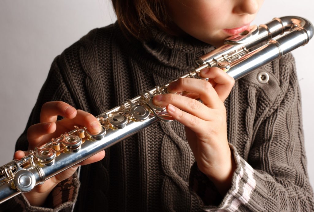 Teen playing flute at home