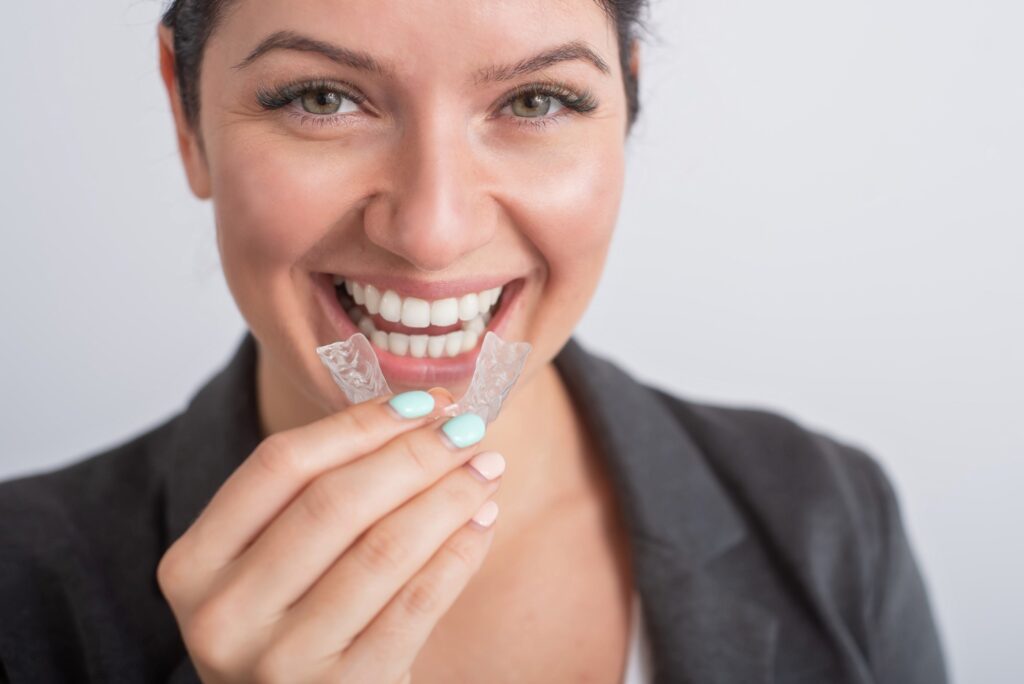 Woman smiling while holding clear aligner