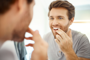 a person examining their teeth in a bathroom mirror